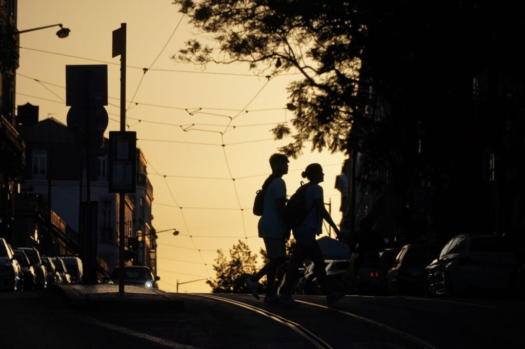 Silhouette of a couple crossing a city street at sunset, creating a dramatic urban scene.