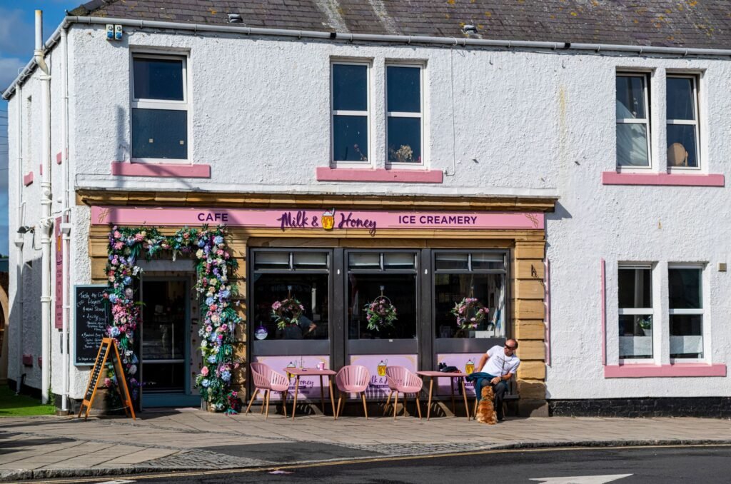 Colorful cafe with floral decor and outdoor seating under bright sunlight.
