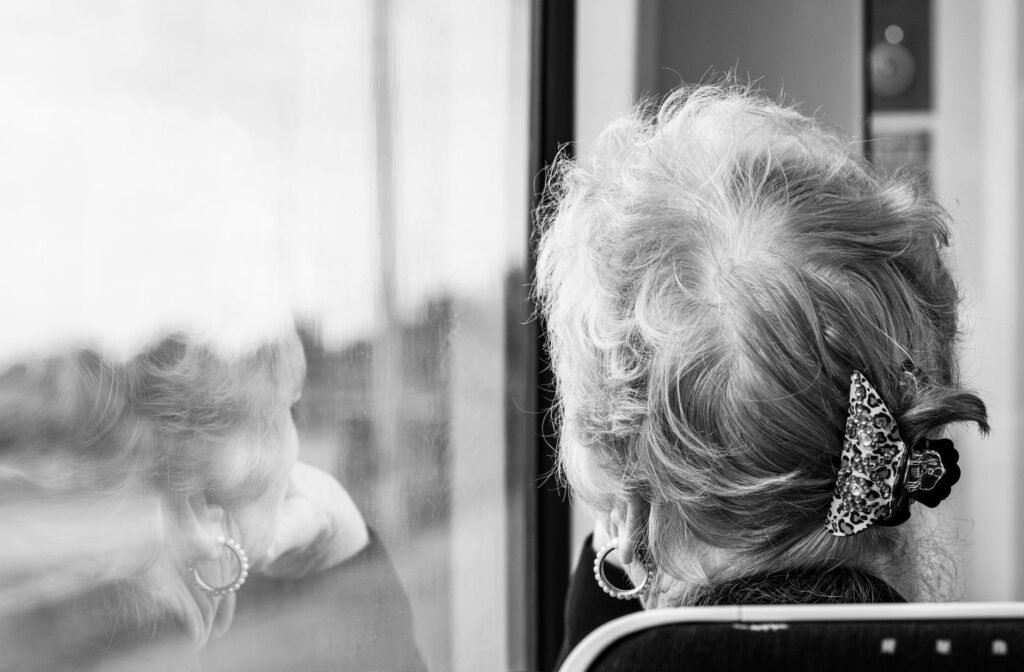 Black and white photo of a woman looking out a train window, reflecting on the view in Blackpool.
