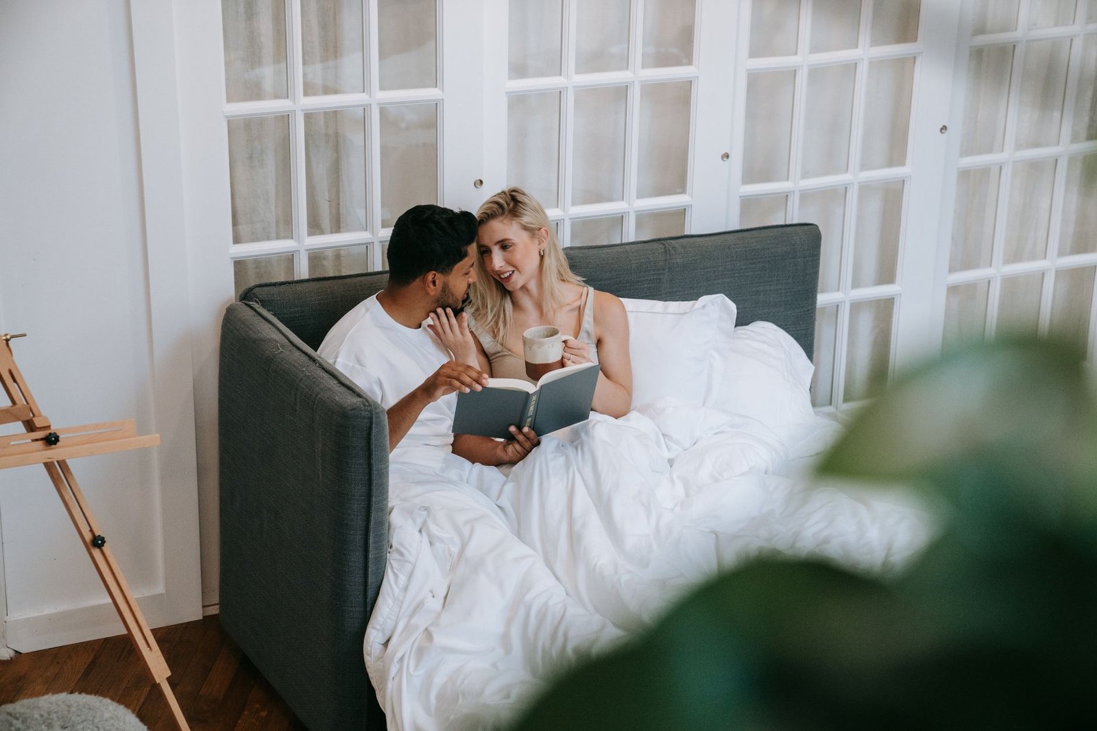A loving couple reading in bed and enjoying coffee, emphasizing domestic tranquility and togetherness.