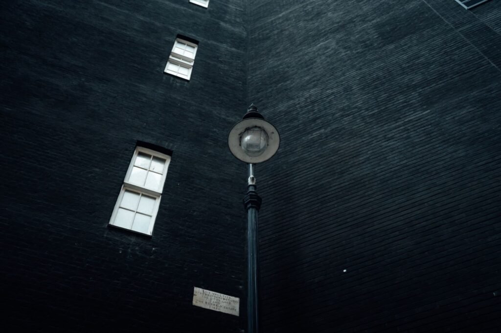 A dramatic street lamp stands tall against a dark brick building in London.