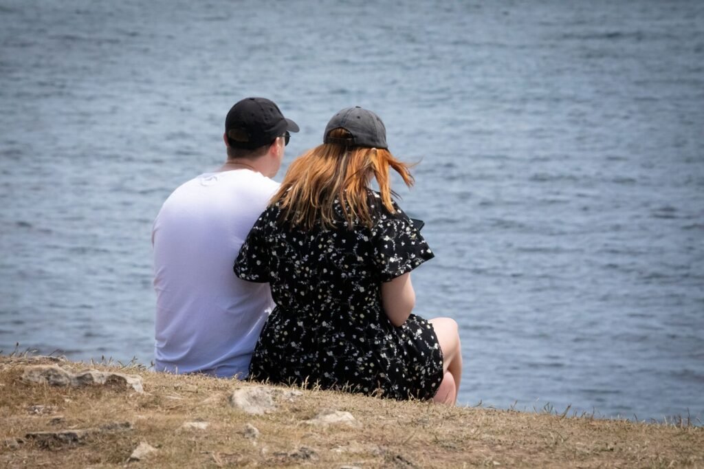 A couple sitting by a peaceful lakeside in England, enjoying the serene outdoor atmosphere.