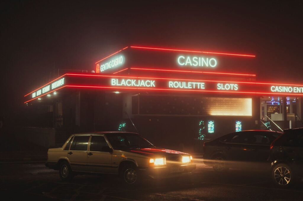 Vintage cars parked outside a neon-lit casino at night, showcasing urban nightlife.