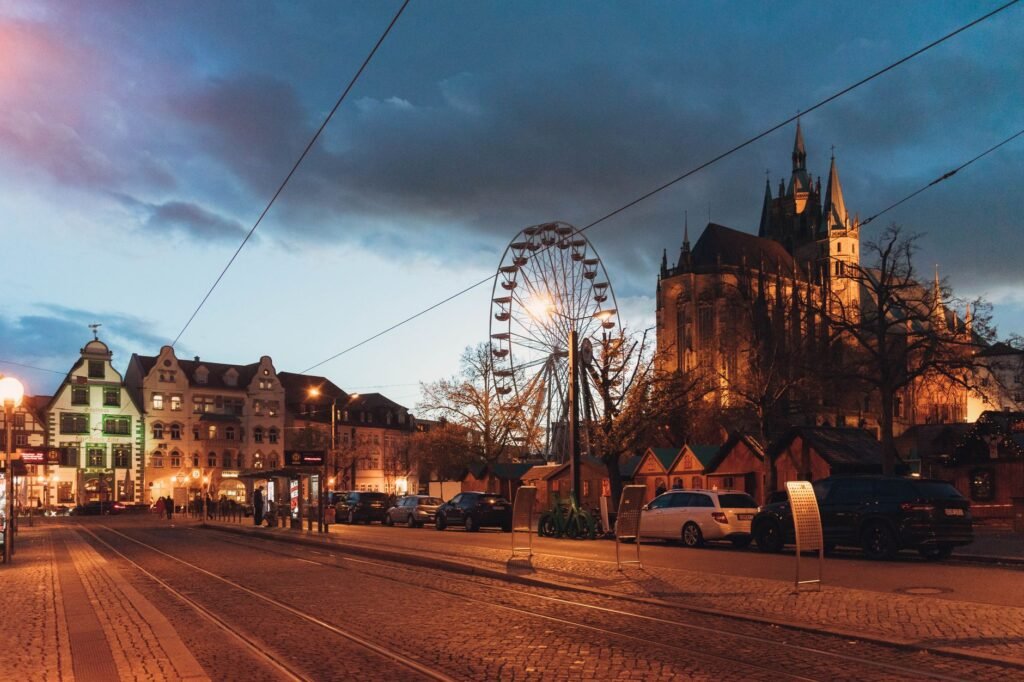 Evening view of Erfurt, Germany, featuring a Ferris wheel and cathedral against a vibrant sky.