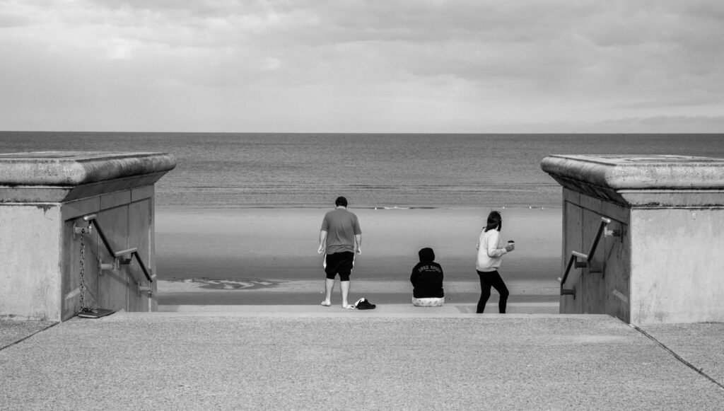Relaxing black and white scene at Blackpool beach with three people enjoying the view.