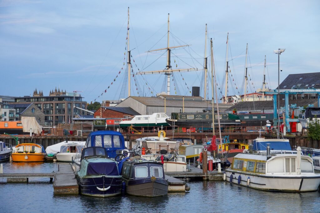 Scenic view of a bustling marina with colorful boats and a historic ship docked.