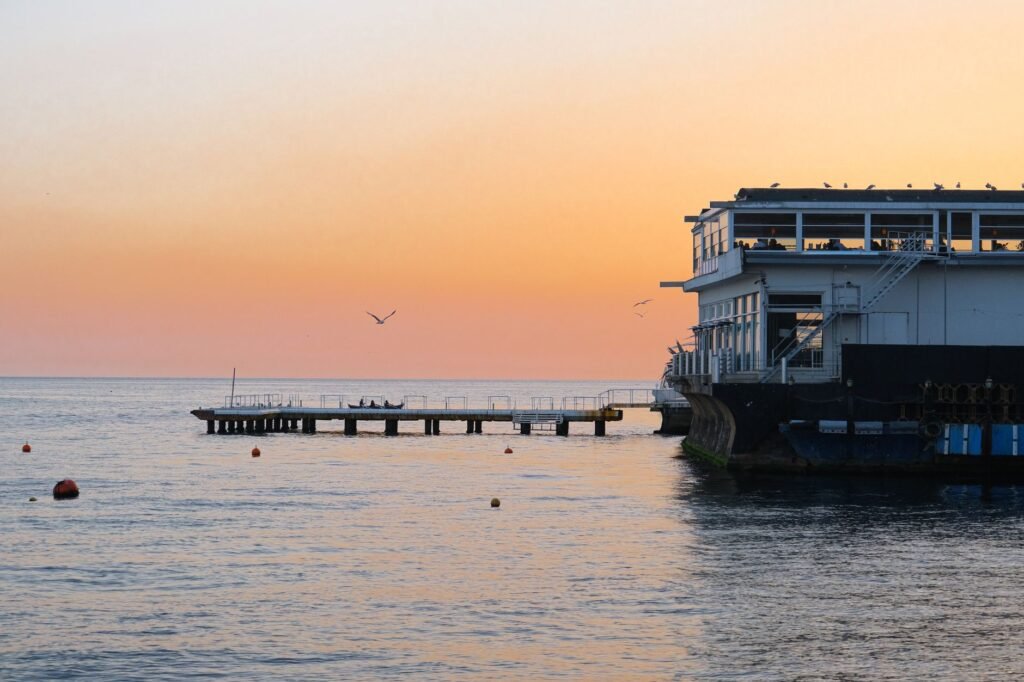 Peaceful sunset by a seaside pier with calm waters and serene ambiance.