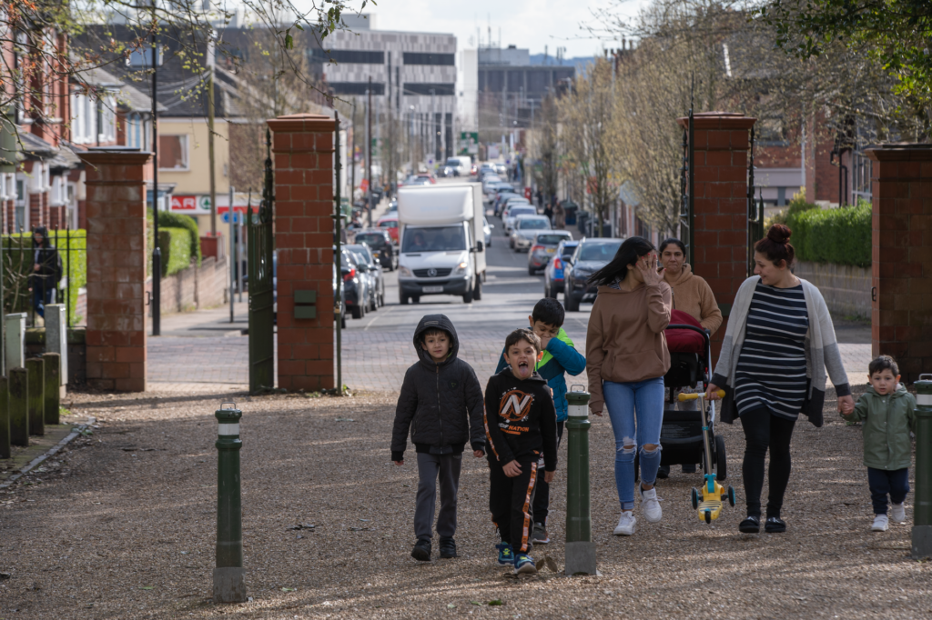 A group of families enjoying a walk on a bustling street in England. Captured during a lively spring day.