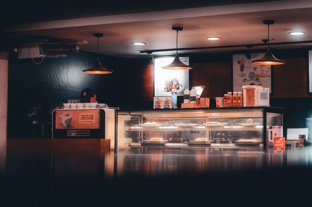 Warm-lit cafe interior showcasing pastries and beverages, creating a cozy atmosphere in Shoolagiri, India.