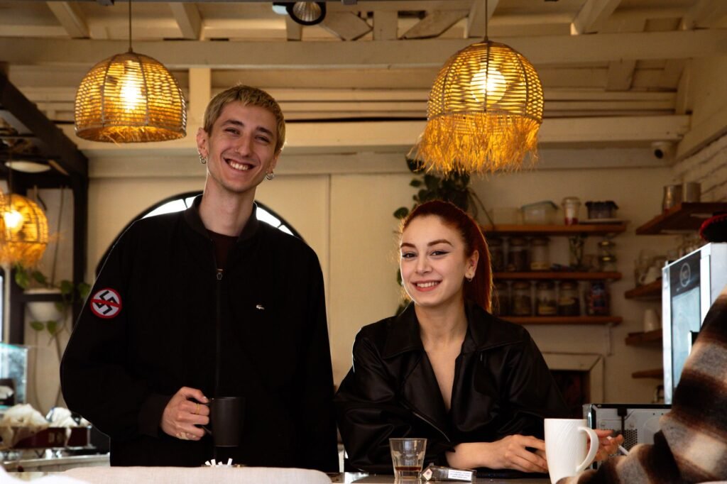 A happy couple in a cozy cafe enjoying drinks under warm lighting.