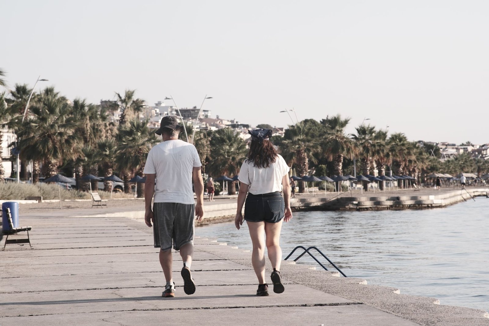 A couple enjoys a walk along the palm-lined waterfront of Foça, İzmir, Türkiye.