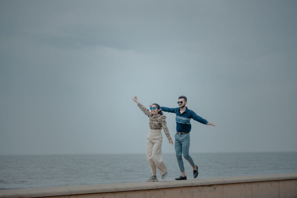 Young couple having fun balancing on a wall with a sea view.
