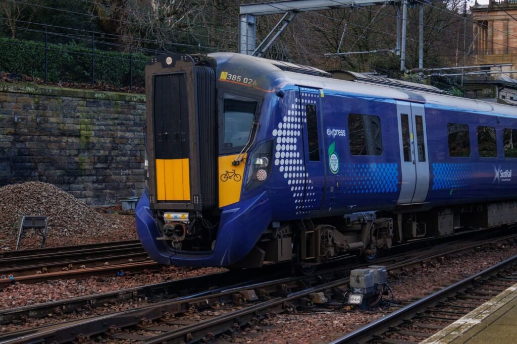 A modern ScotRail train captured at a station in Scotland, highlighting its sleek design and vibrant colors.
