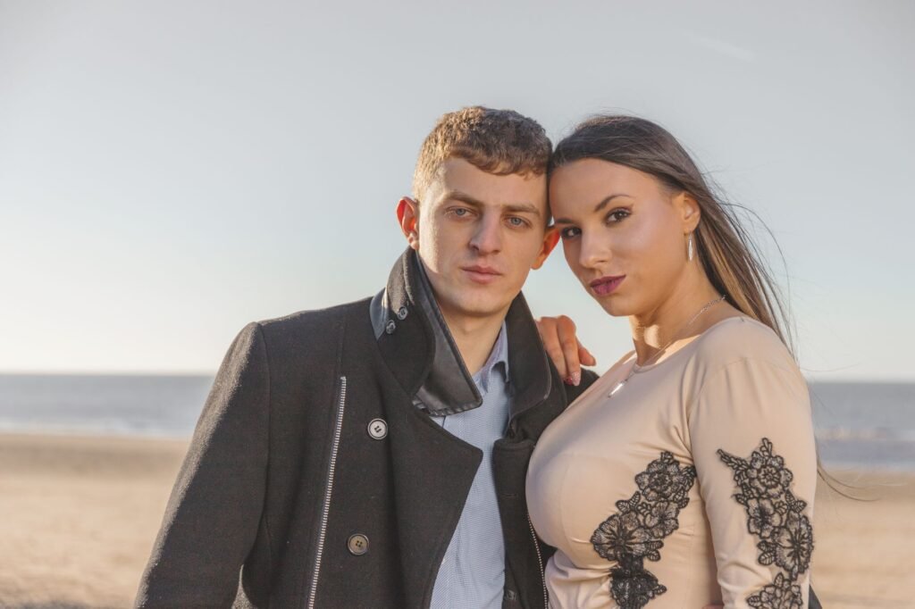 A couple enjoys a serene moment on the beach, portraying love and intimacy with the ocean as their backdrop.