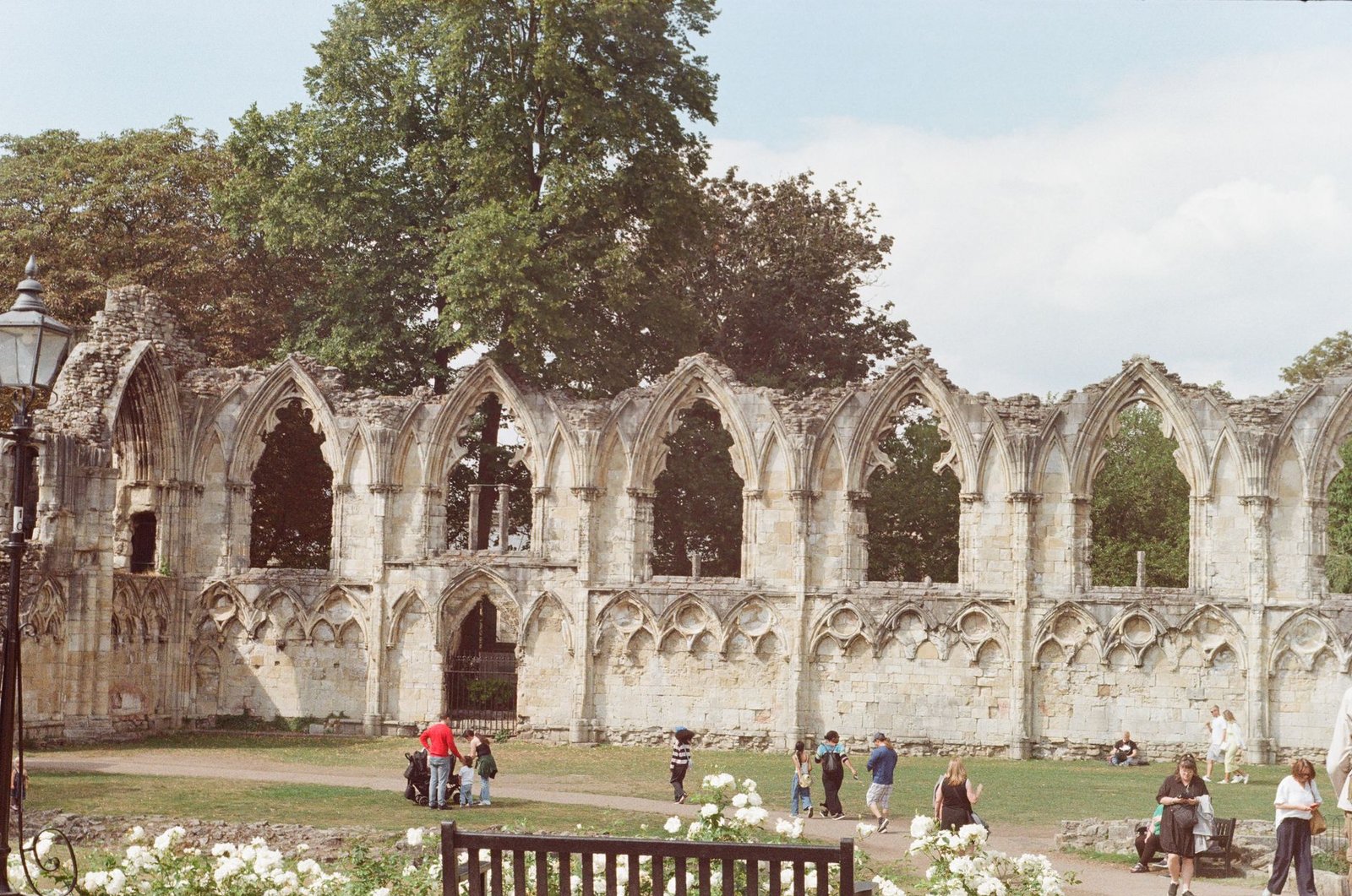 Visitors explore the medieval ruins of St. Mary's Abbey on a sunny day in York, England.