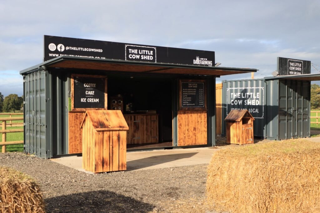 A rustic coffee shop setup outdoors in the English countryside offering coffee, cake, and ice cream.