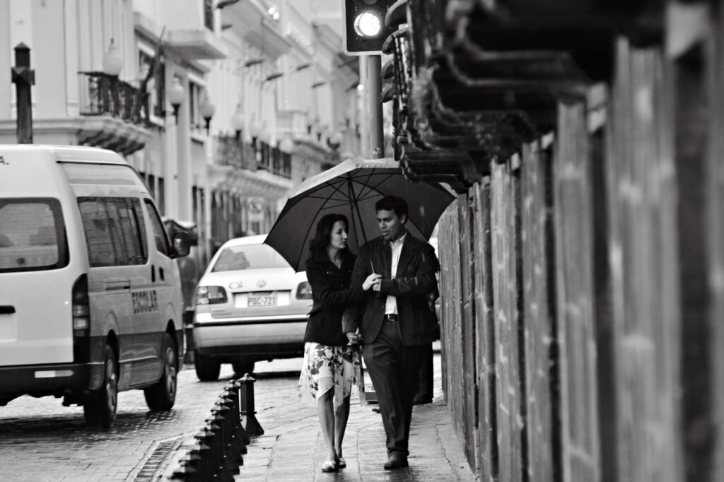 Man and woman walking under an umbrella on a rainy street in Quito, Ecuador.