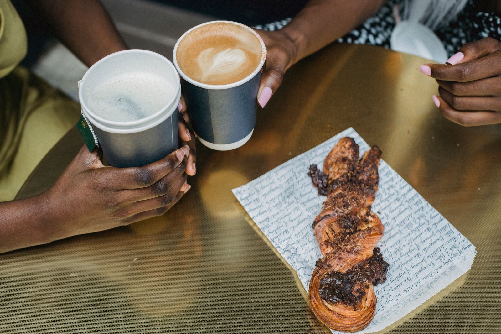 Two women enjoying coffee and pastry at a café, capturing a cozy social moment.