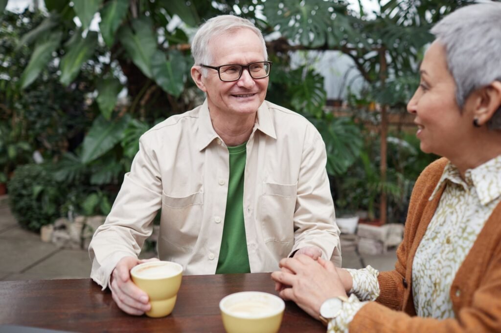 Happy senior couple sharing coffee and conversation in a lush garden setting.
