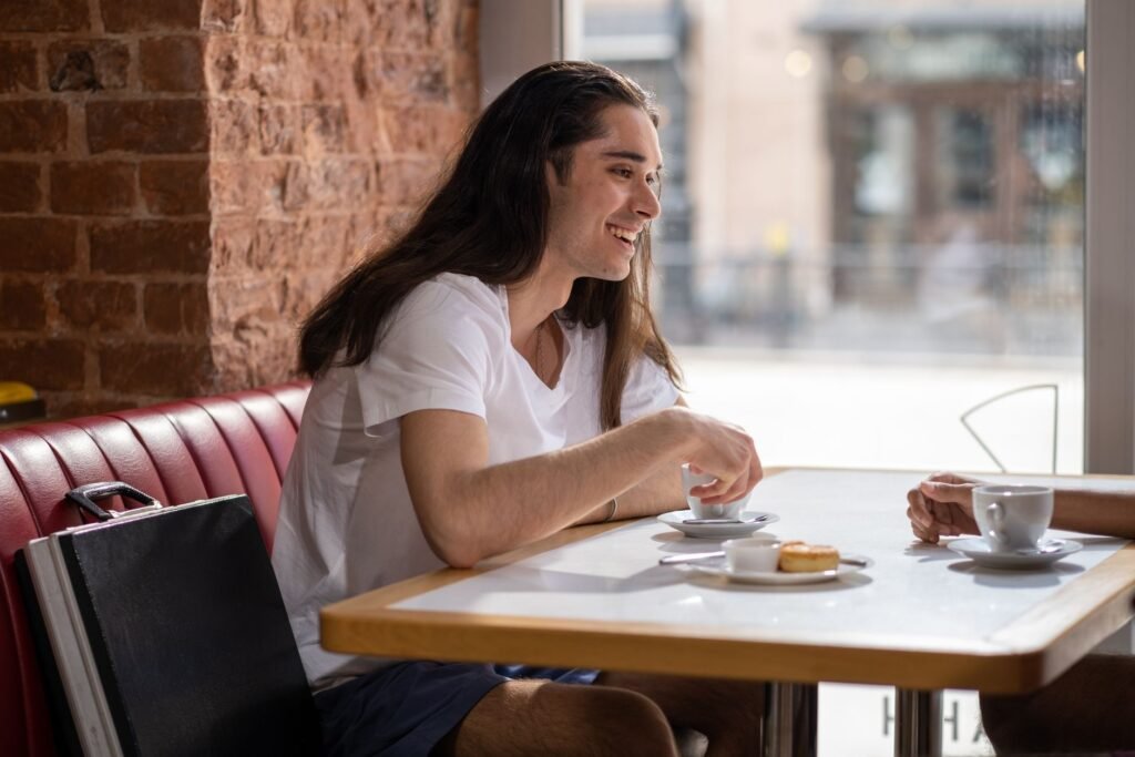 Young man enjoying a casual coffee meeting indoors with a friend in a cozy café setting.