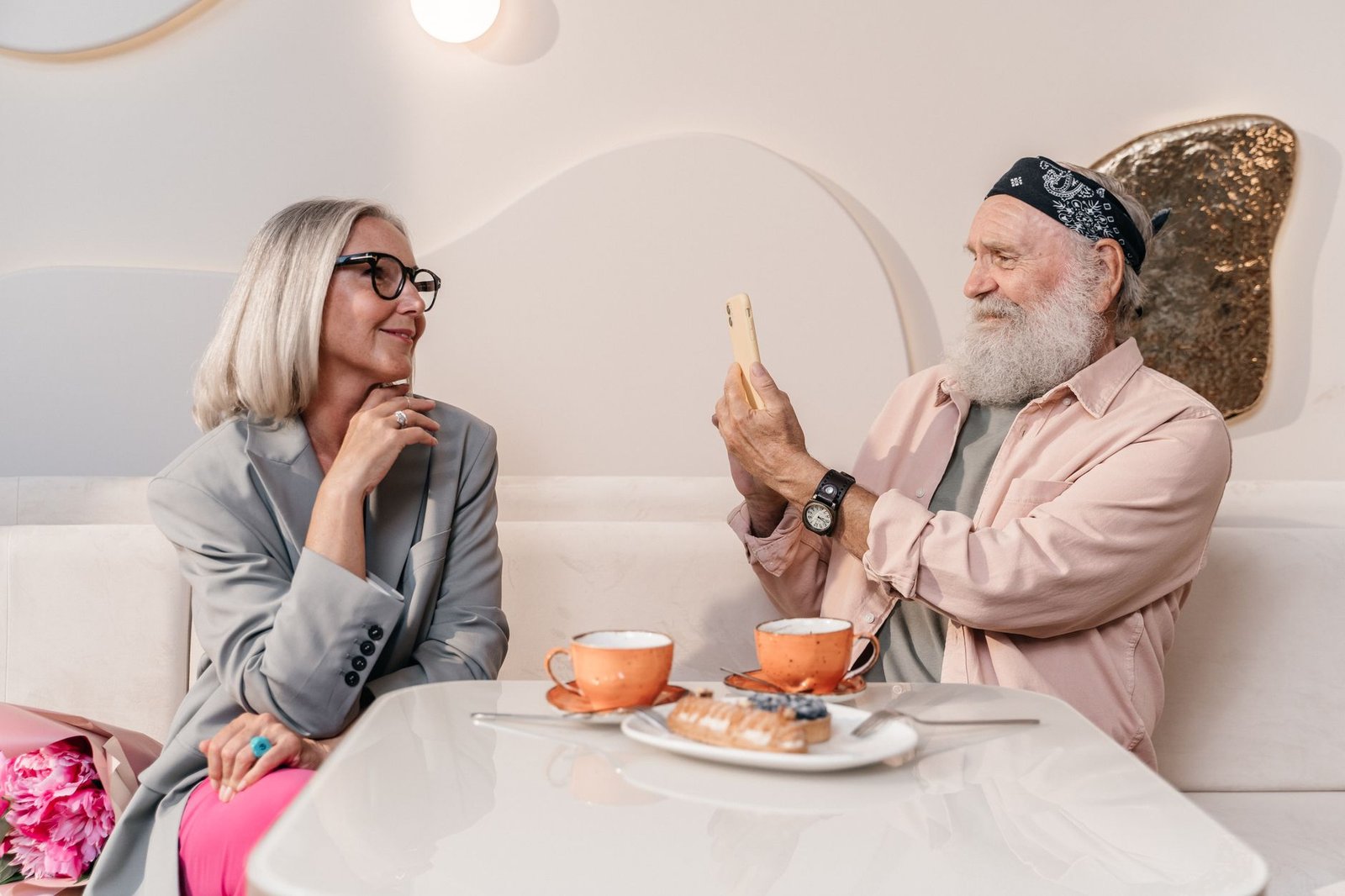 Senior couple in a stylish cafe enjoying each other's company over coffee and pastries.