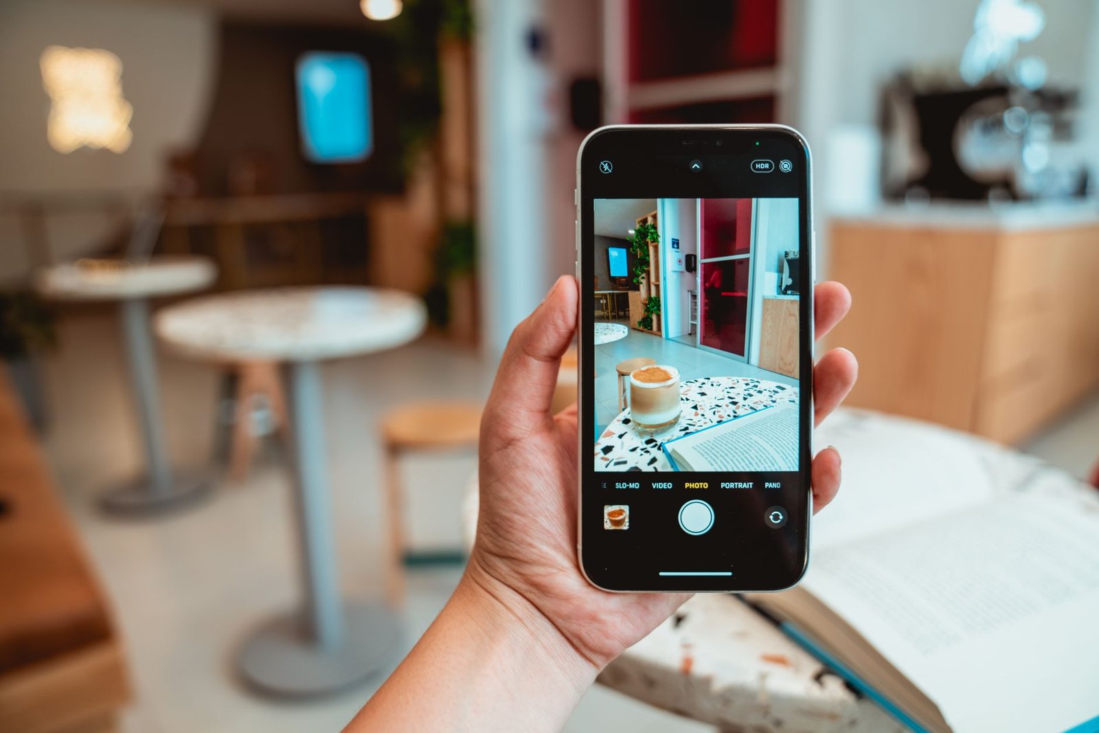 A person photographing coffee with a smartphone in a modern cafe setting.