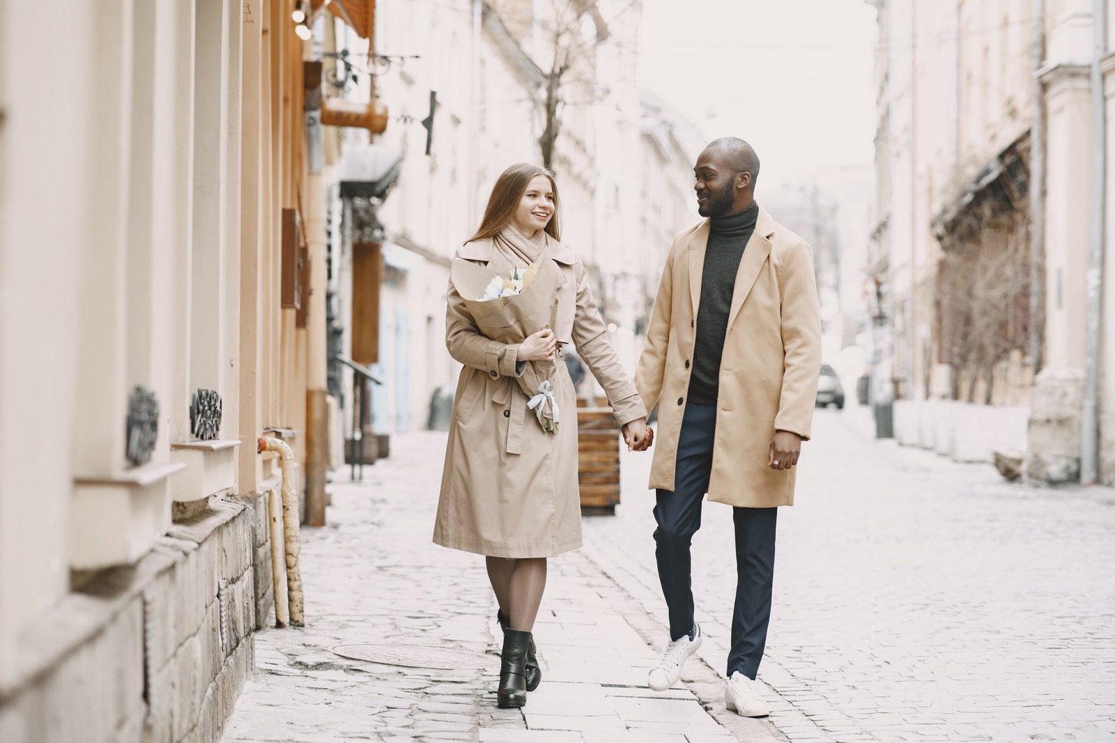 Happy interracial couple enjoying a romantic walk on a picturesque cobblestone street. Perfect for lifestyle content.