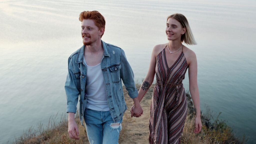 A happy couple walks hand in hand by a tranquil lakeside, enjoying a romantic evening together.