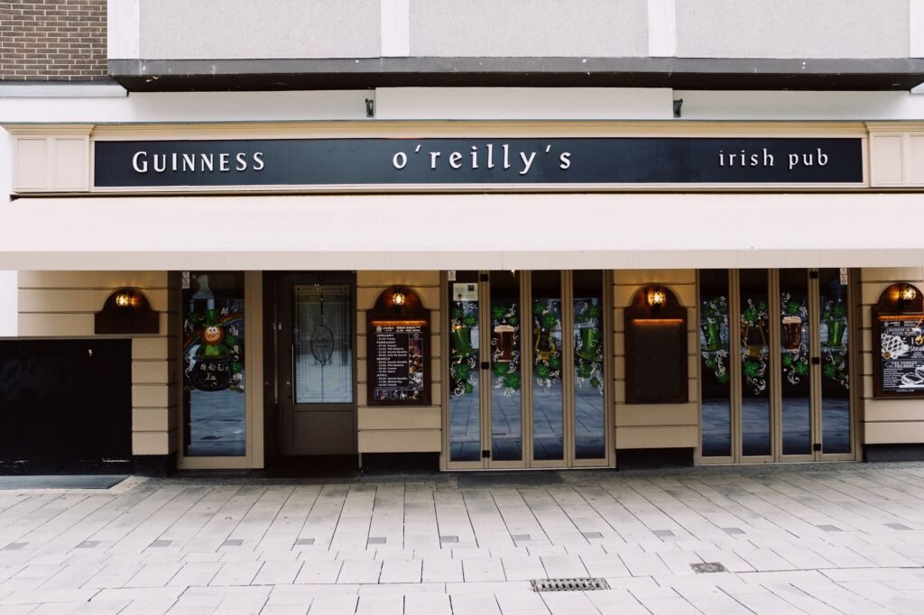 Exterior of modern bar building with mirrored windows decorated with wide signboard and menu on chalkboards below lanterns in