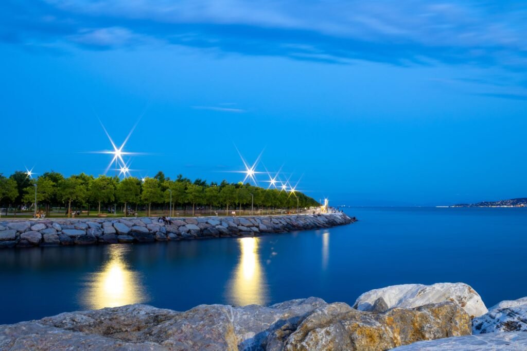 Beautiful twilight scene of a waterfront promenade with glowing lights and calm waters.