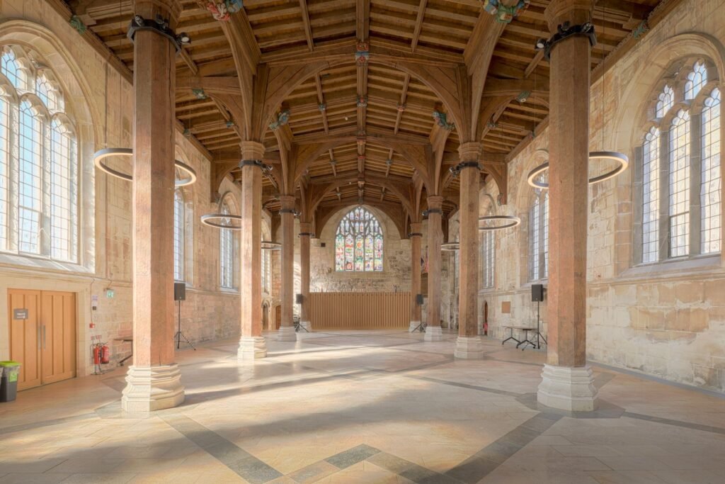 Beautiful interior view of the historic Guildhall in York, England, showcasing timber beams and stone walls.