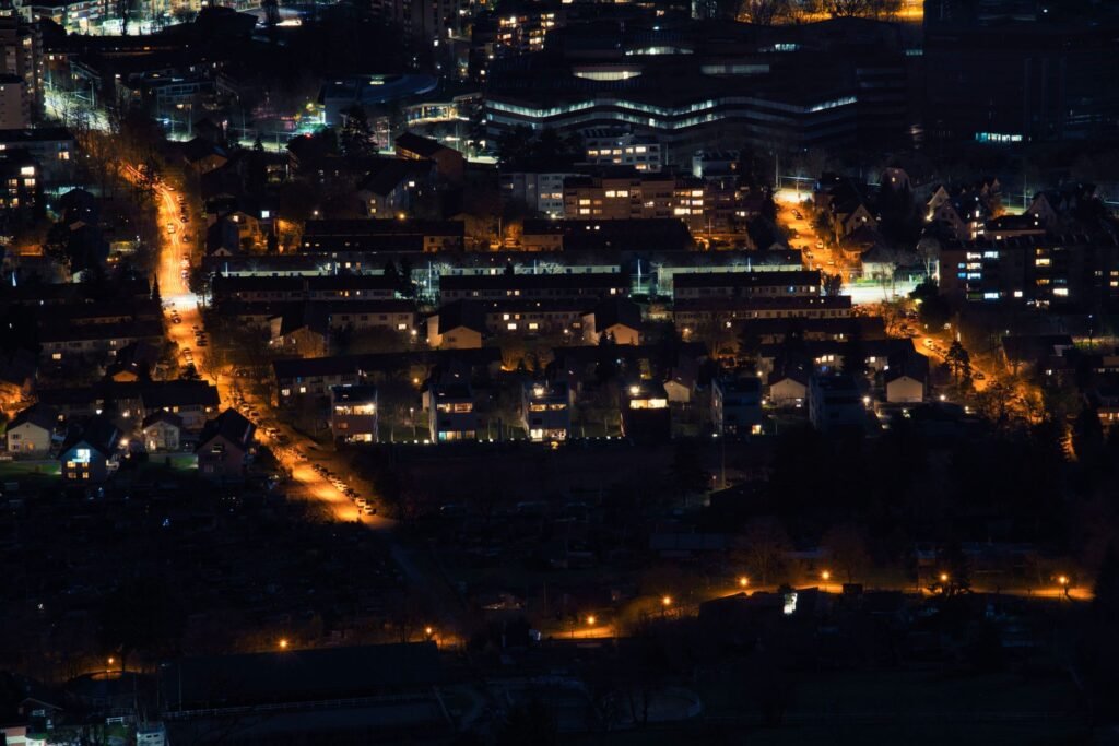 Dark aerial view of city streets illuminated by streetlights at night.