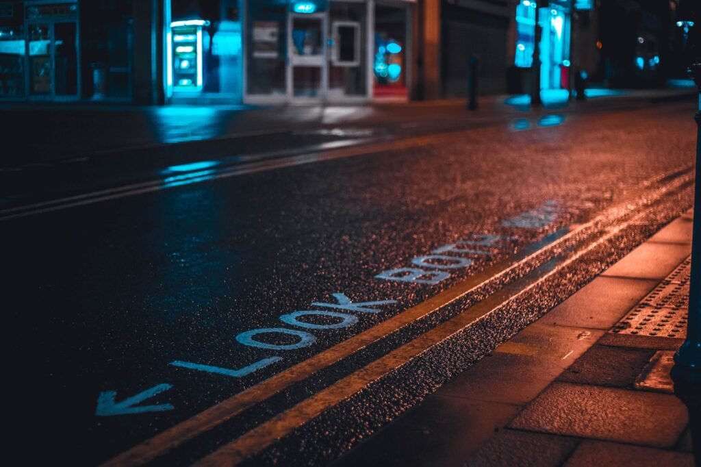Rain-drenched street with neon light reflections and 'Look Both Ways' text.