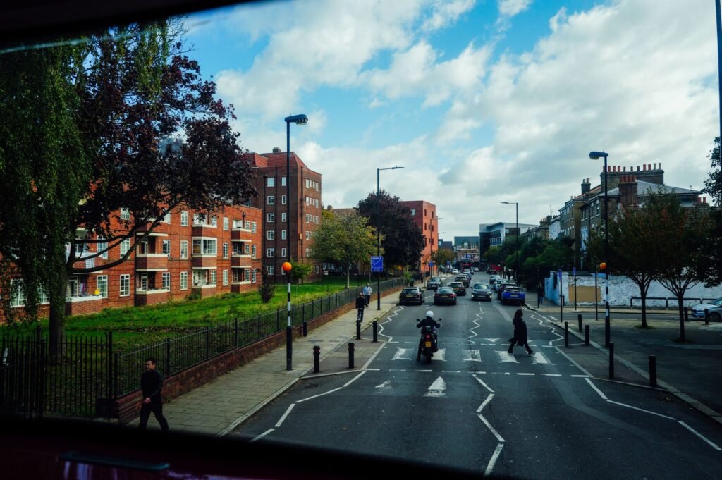 Vibrant city street with pedestrians, vehicles, and red brick buildings on a sunny day.