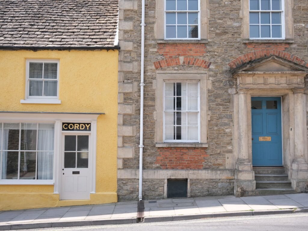 Vibrant street view of charming English village architecture featuring yellow and stone buildings.
