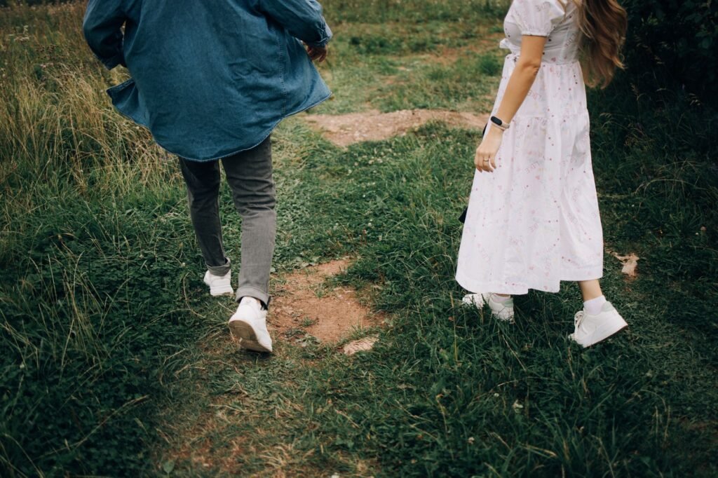 A young couple enjoys a walk on a grassy path during a warm summer day.