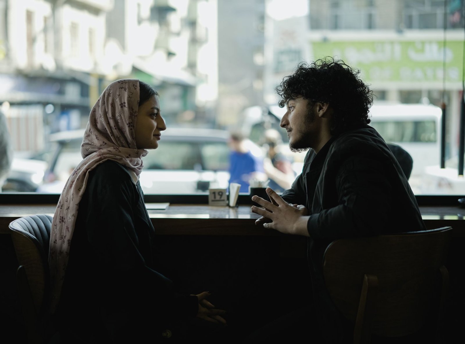 Two adults engage in a deep conversation over coffee in a cozy cafe setting.