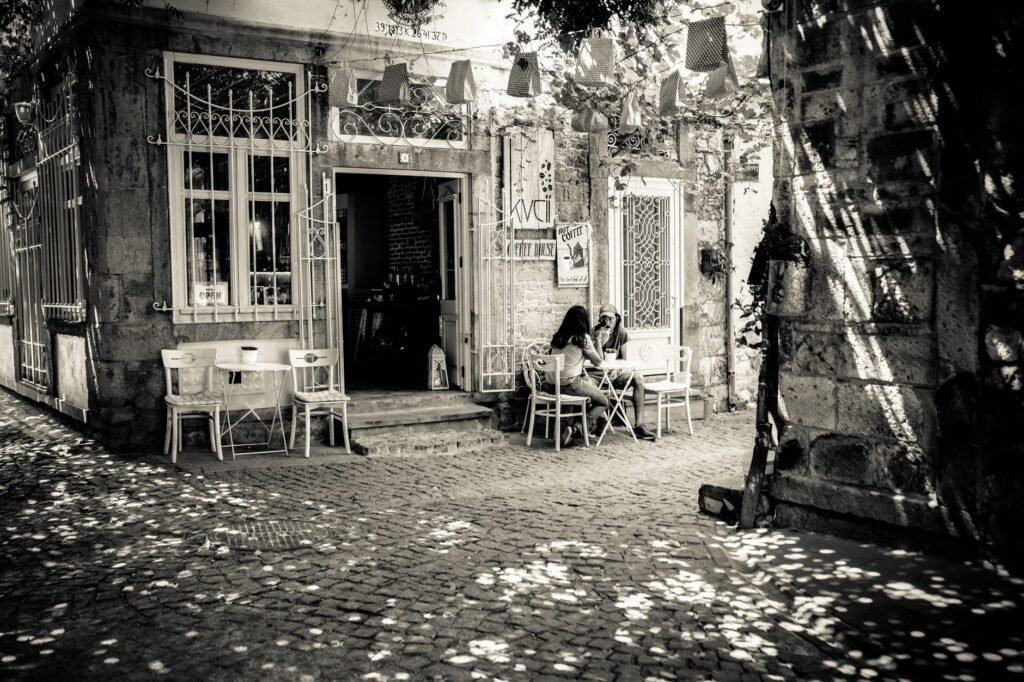 A cozy outdoor café setting with vintage charm, featuring a couple seated amidst dappled sunlight.