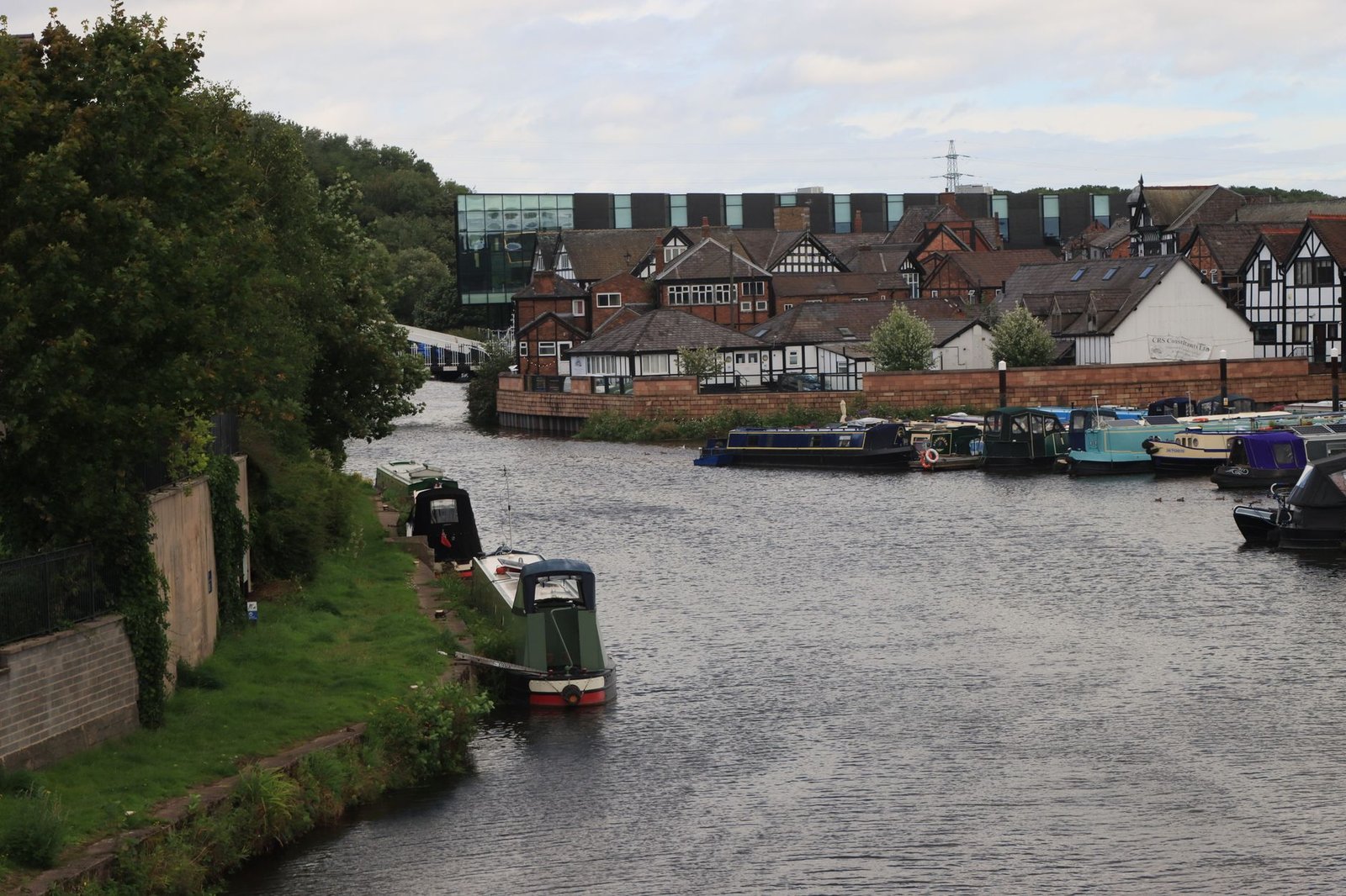 Scenic view of the canal and historic buildings in Northwich, England. Tranquil waterway with boats and Tudor architecture.